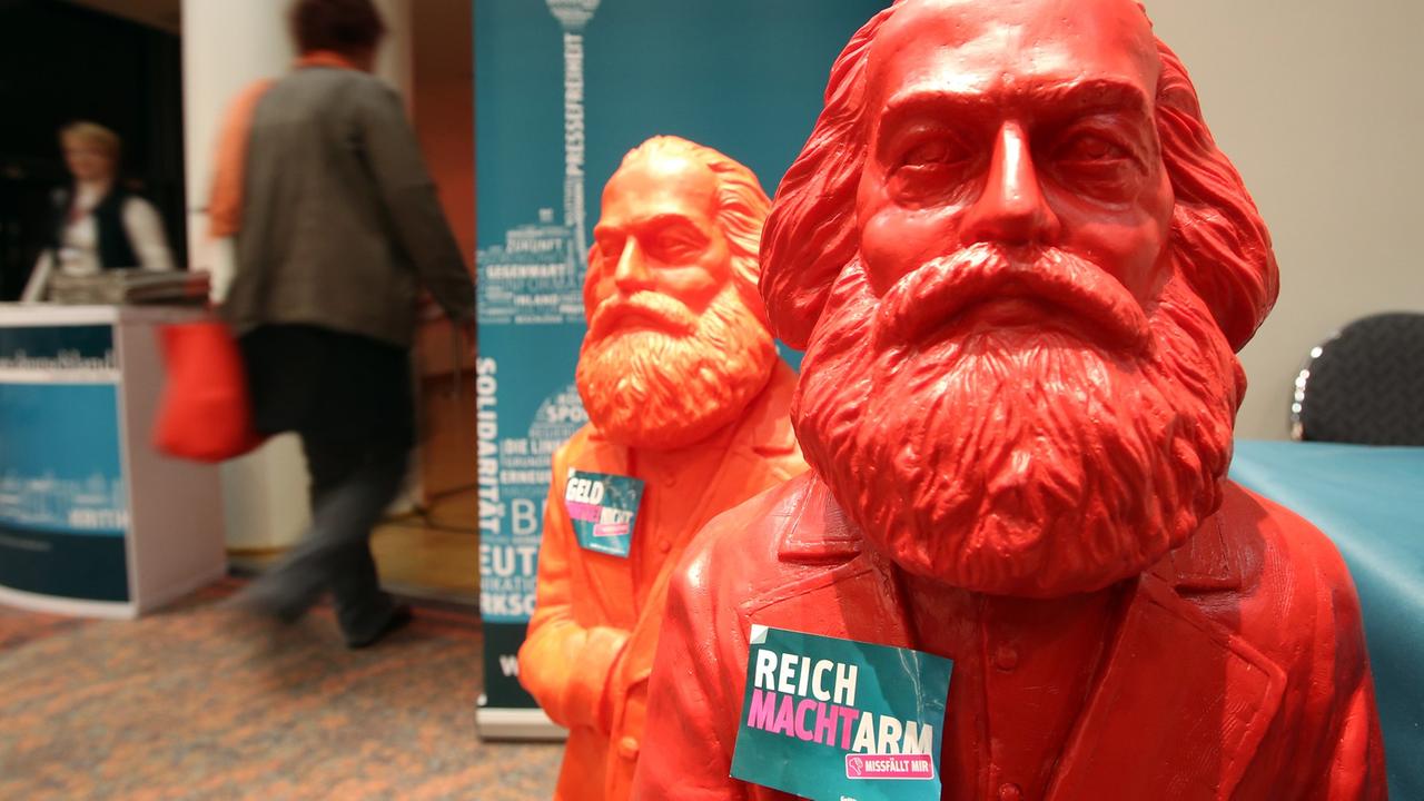 Rote Plastikfiguren von Karl Marx mit dem Slogan "Reich macht arm - Missfällt mir" sind  im Februar 2014 vor dem Bundesparteitag der Partei Die Linke in Hamburg zu sehen.