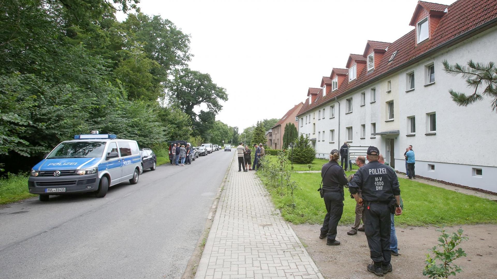 Einsatzkräfte der Polizei stehen vor einem Mehrfamilienhaus in Boldebuck bei Güstrow in Mecklenburg-Vorpommern.