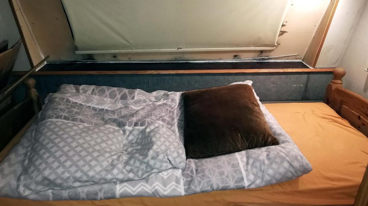 Ein Holzbett steht in einem Wohnwagen.