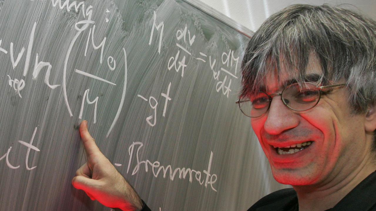 Der Physiker Metin Tolan steht an der Tafel in seinem Büro an der Universität in Dortmund und erklärt die sogenannte Raketengleichung.