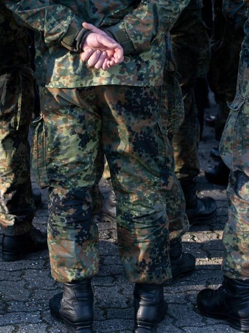 Mehrere Soldaten der Bundeswehr in Uniform von hinten mit den Händen auf dem Rücken