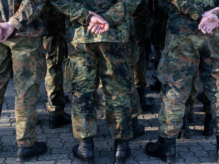 Mehrere Soldaten der Bundeswehr in Uniform von hinten mit den Händen auf dem Rücken