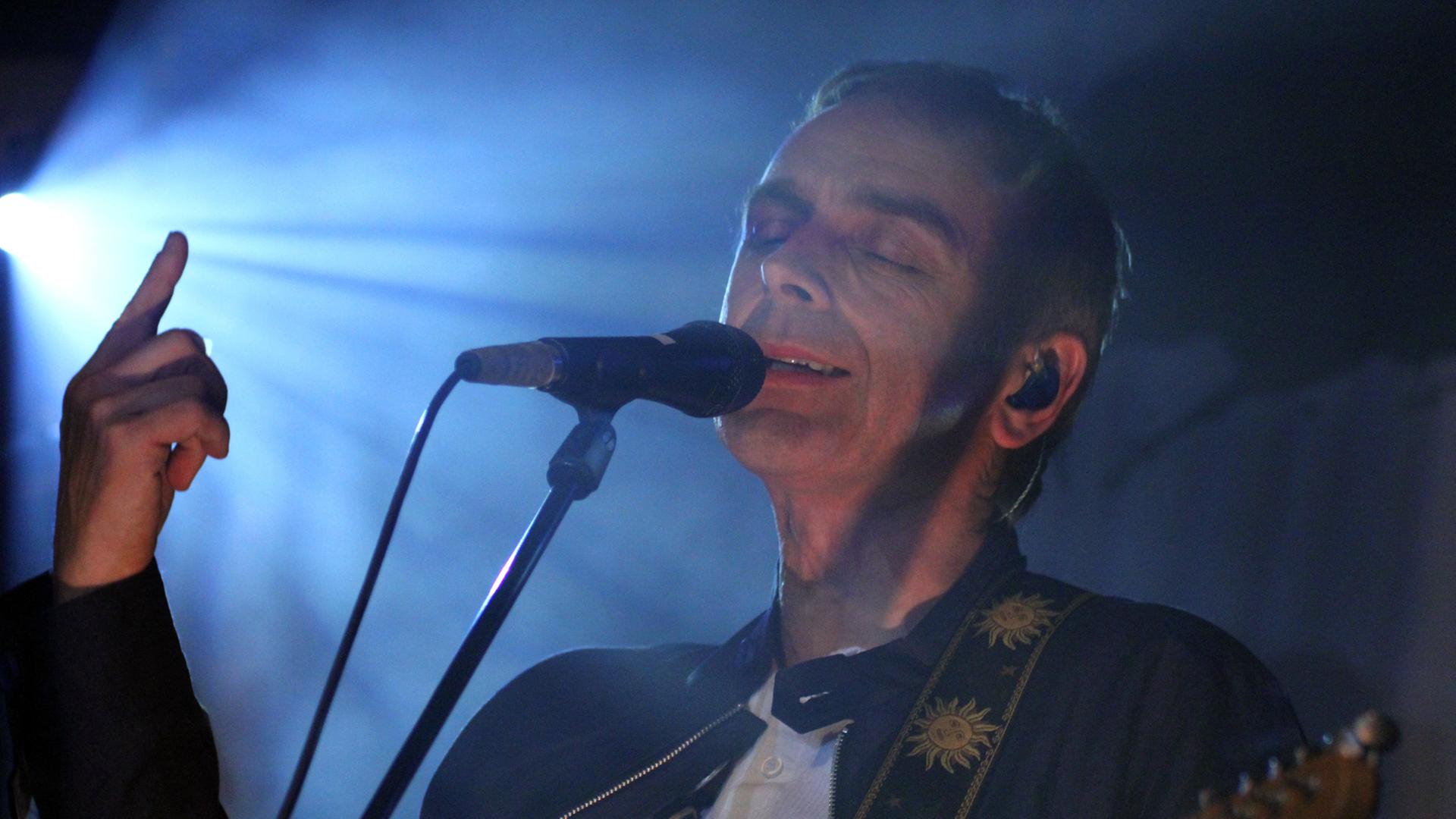 Karl Hyde, Kopf und Sänger der britischen Band "Underworld" im Scheinwerferlicht am Mikro bei einem Konzert