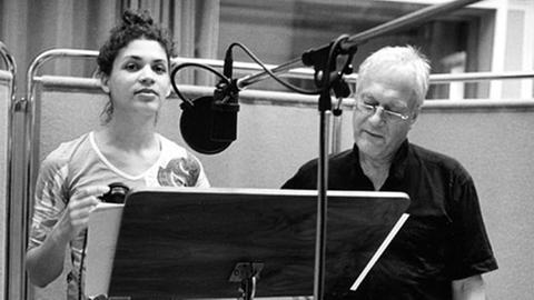 Regisseur Ulrich Gerhardt mit Schauspielerin Isabelle Redfern im Studio bei einer Tonaufnahme stehend am Pult mit Mikrophon 