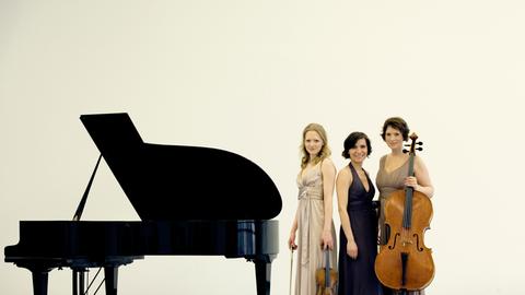 Das Boulanger Trio steht neben einem Klavier.
