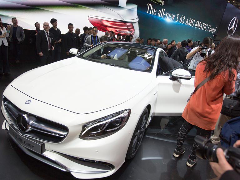 Fotografen, Journalisten und eine Messehostess stehen um einen weißen AMG-Mercedes.