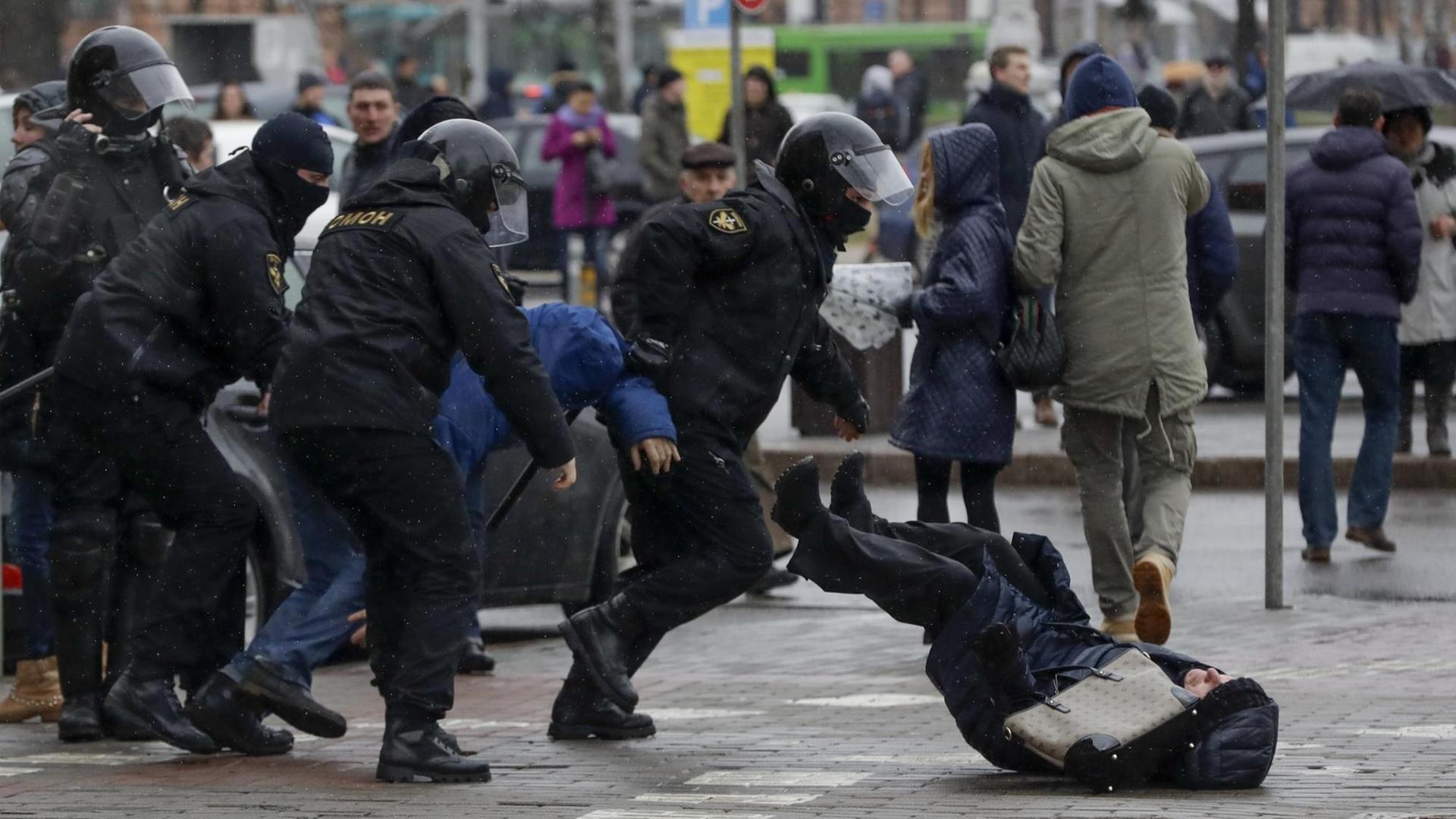 Polizisten stoßen am 25.03.2017 in Minsk (Weißrussland) auf einer Demonstration eine Teilnehmerin um.