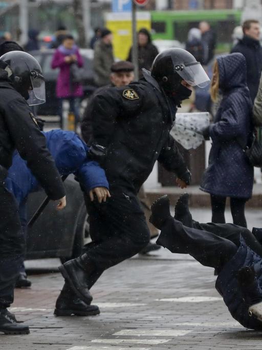 Polizisten stoßen am 25.03.2017 in Minsk (Weißrussland) auf einer Demonstration eine Teilnehmerin um.