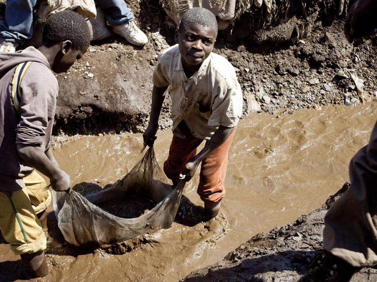 Zu sehen sind Kinder, die in einer Kupfermine arbeiten. Sie stehen bis zu den Knien im Schlamm.
