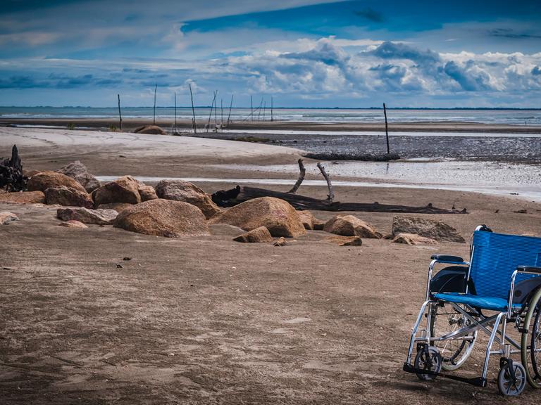 Verliert ein eingeschränktes Leben seinen Wert? Ein blauer Rollstuhl an einem Strand.