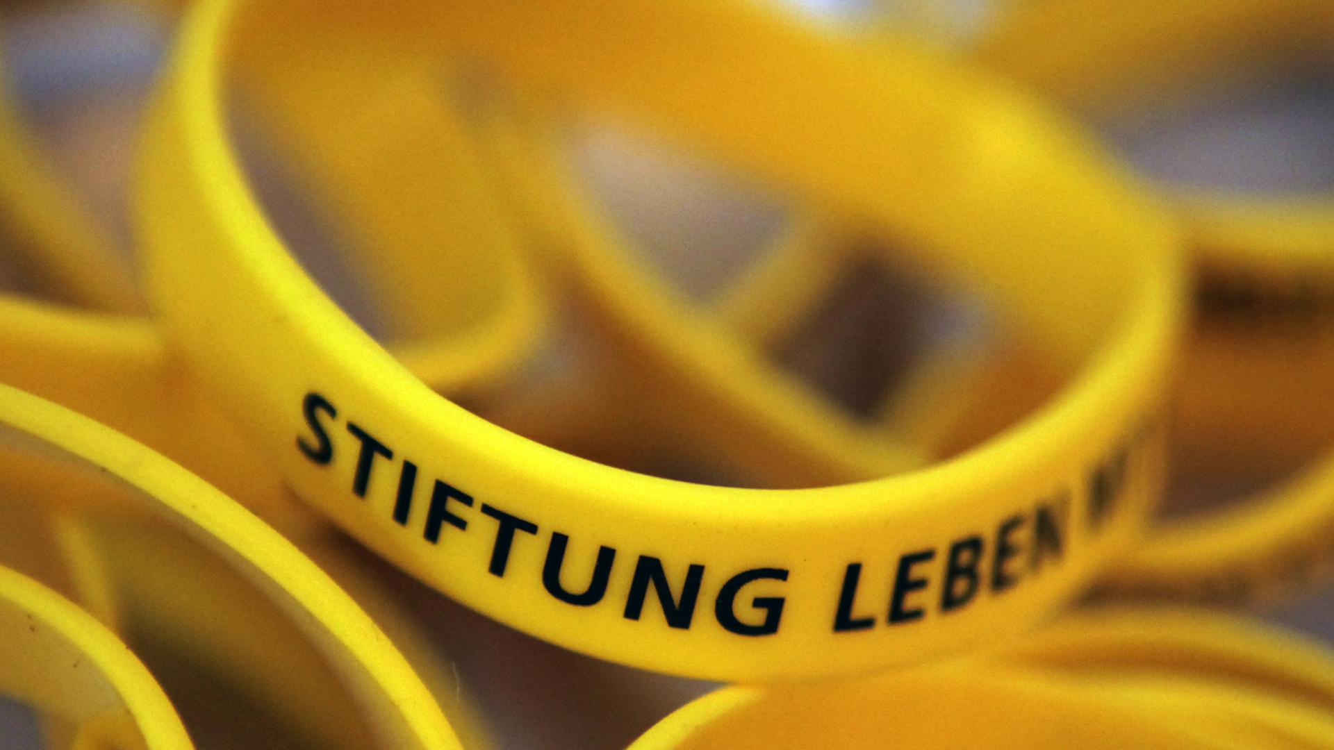 Gelbe Gummiarmbänder mit der schwarzen Aufschrift "Stiftung Leben"