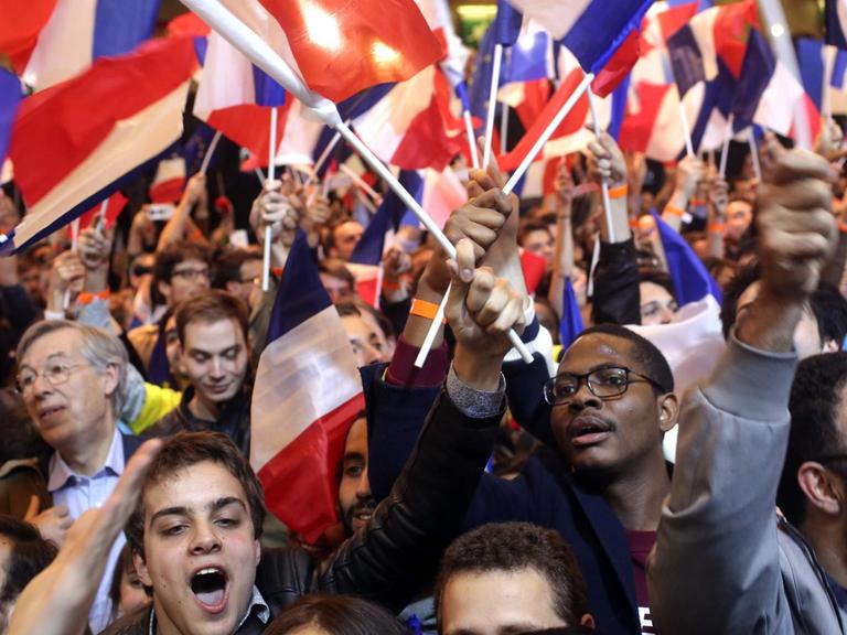 Unterstützer des französischen Präsidentschaftskandidaten Emmanuel Macron bejubeln in Paris mit französischen Flaggen die ersten Hochrechnungen.