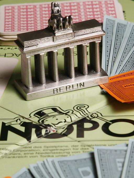 Ein Modell des Brandenburger Tores steht am Montag (02.04.2007) in Berlin auf einem Monopoly-Brettspiel inmitten von Karten, Würfeln und Spielgeld-Scheinen.