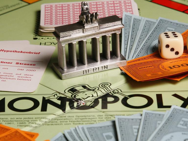 Ein Modell des Brandenburger Tores steht am Montag (02.04.2007) in Berlin auf einem Monopoly-Brettspiel inmitten von Karten, Würfeln und Spielgeld-Scheinen.