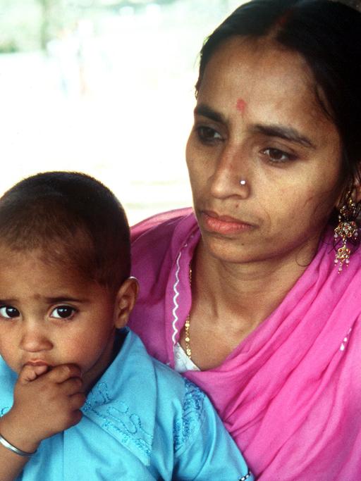 Eine indische Mutter in einem rosa-farbenem Sari mit ihrem kleinen Kind, aufgenommen 1980.