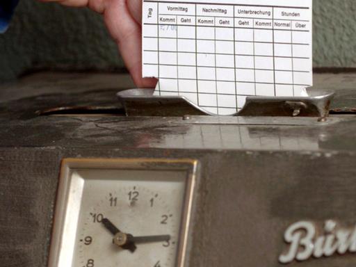 Eine Hand steckt Montag (29.03.2004) in einem Krefelder Unternehmen eine Karte in ein Arbeitszeiterfassungsgerät.