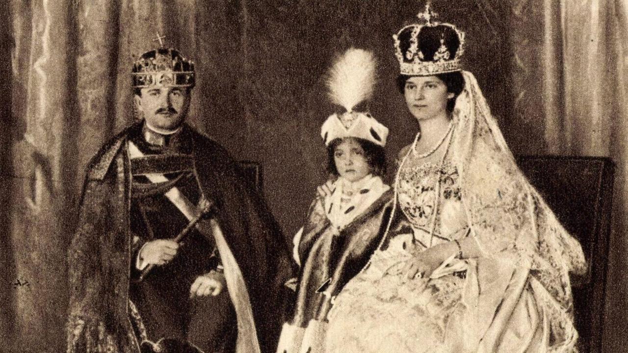 Kaiser Karl I. von Österreich in einer schwarzweißen Porträtaufnahme mit Familie in prunkvoller monarchistischer Montur.