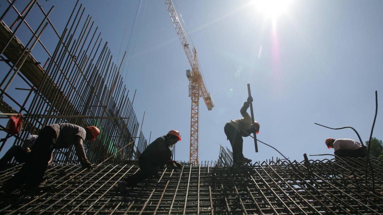 Bauarbeiter bei Dacharbeiten in der Sonne an einem heißen Sommertag