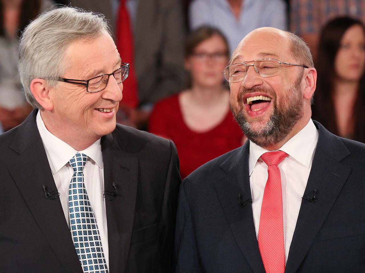 Jean-Claude Juncker und Martin Schulz lachen im Fernsehstudio miteinander