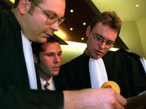 Vor der Verkündung des sogenannten Bosman-Urteils stecken der belgische Fußball-Profi Jean-Marc Bosman (m) und zwei seiner Anwälte, Marc Lucan (l) und Jean-Claude Dupont die Köpfe zusammen.