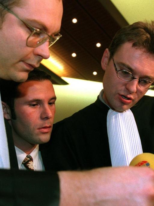 Vor der Verkündung des sogenannten Bosman-Urteils stecken der belgische Fußball-Profi Jean-Marc Bosman (m) und zwei seiner Anwälte, Marc Lucan (l) und Jean-Claude Dupont die Köpfe zusammen.