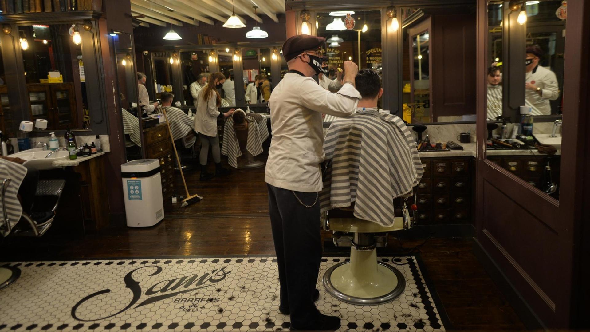 Ein Friseur mit Maske schneidet einem Kunden die Haare.