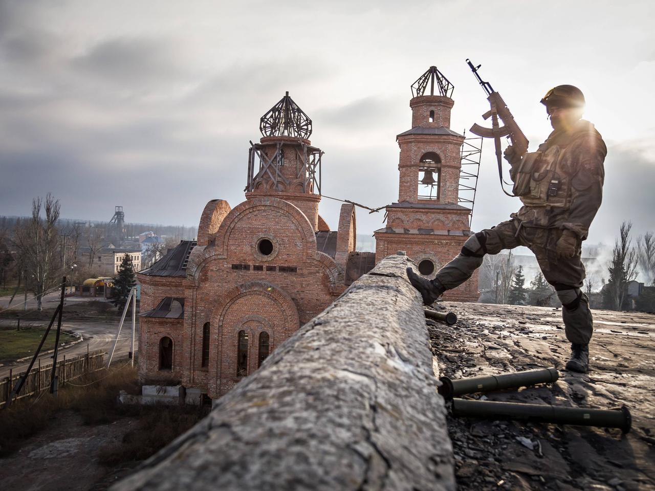 Soldat vor zerstörter Kirche im ukrainischen Dorf Pisky.