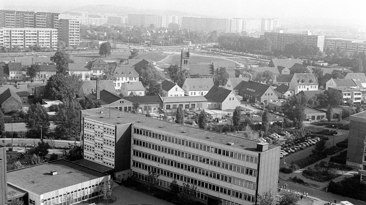 Schwarzweiß-Luftaufnahme von Marzahn: In der Mitte zu sehen sind dorfartige Hausanordnungen, darum Neubauten und Hochhäuer.