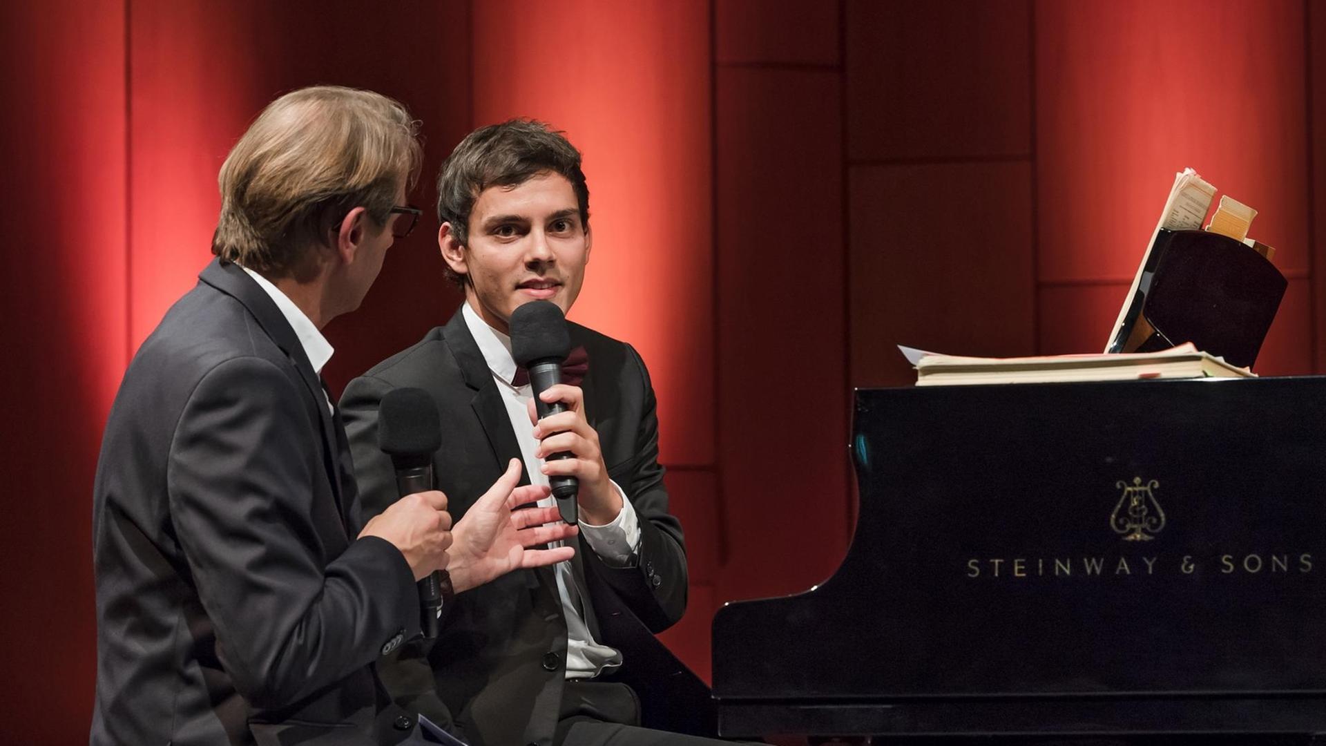 Pianist Aaron Pilsan und Moderator Christoph Schmitz sitzen am Flügel im Bürgerhaus Bremen-Vegesack im Gespräch über Beethovens 12. Klaviersonate