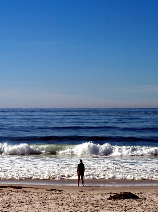 Eine Mann steht am Pazifikstrand von Carmel in Kalifornien.