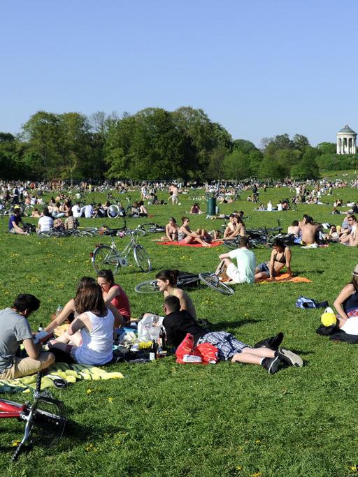 Viele Ausflügler sitzen im Englischen Garten in München auf einer Wiese.