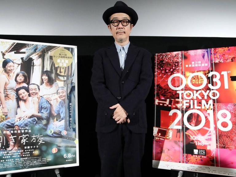 Darsteller Lily Franky beim Tokyo Filmfestival, während der Vorstellung des Films "Shoplifters". Er steht neben einem Filmplakat.
