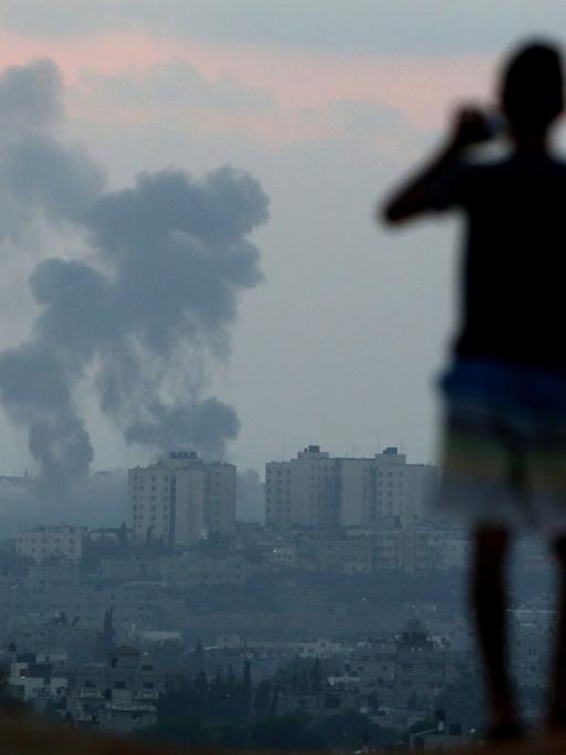 Menschen betrachten eine Explosion im Gaza-Streifen