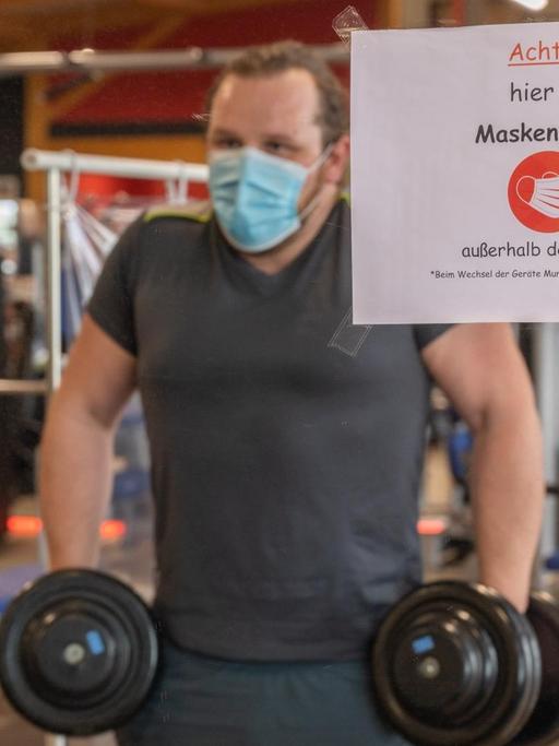 Ein Mann trainiert mit Mund-Nasen-Schutz in einem Fitnessstudio.