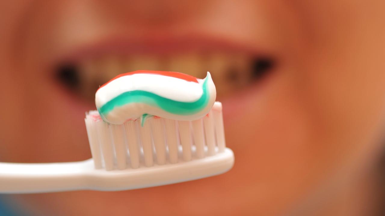 Eine Zahnbürste mit Zahnpasta vor einem Mund