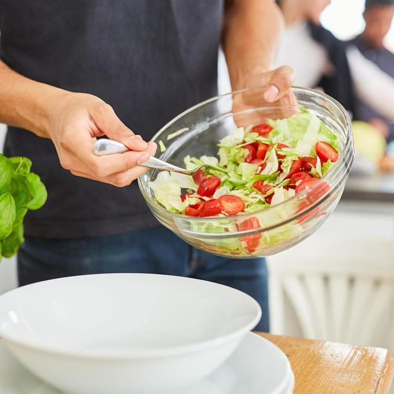 Mann mit Schüssel frischem Salat in Küche vor dem gemeinsamen Mittagessen in einer WG