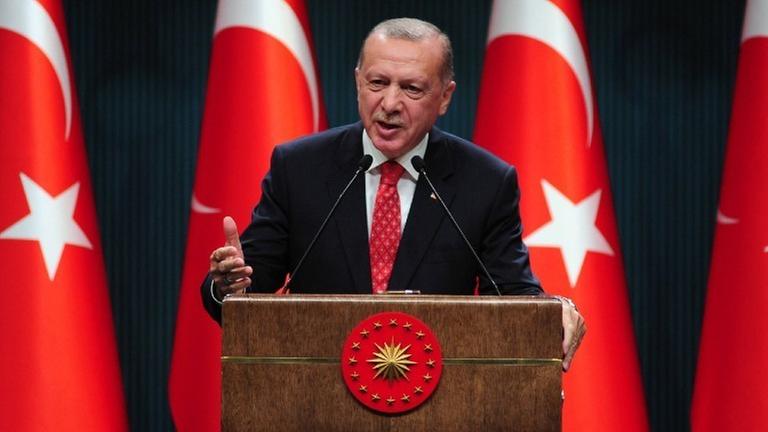 Der türkische Präsident Erdogan an einem Rednerpult vor mehreren türkischen Flaggen. 