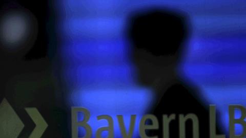 Hinter dem Logo der Bayern LB steht Bank-Zentrale in München ein Mann.