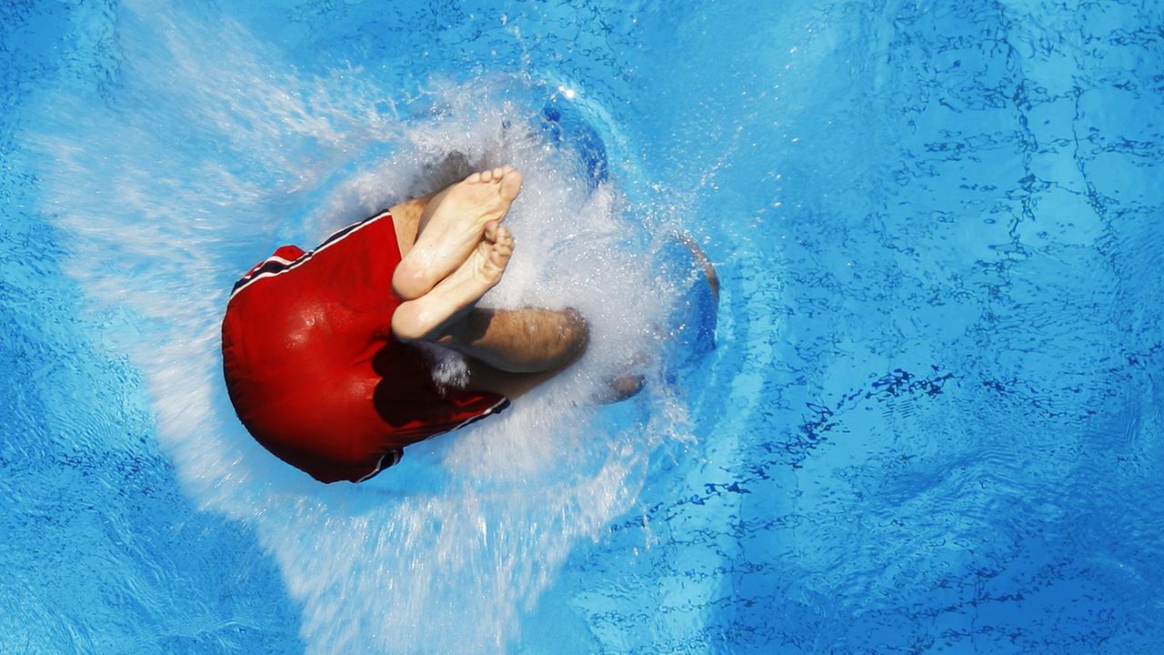 Ein Junge springt in Berlin im Sommerbad Neukölln vom Sprungturm ins erfrischende Wasser. Ein Junge springt in Berlin im Sommerbad Neukölln vom Sprungturm ins erfrischende Wasser.