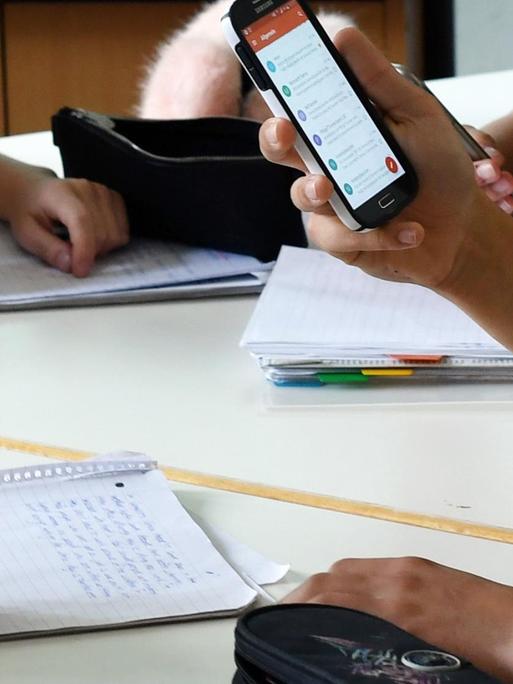 Schüler hält im Unterricht ein Handy in den Händen