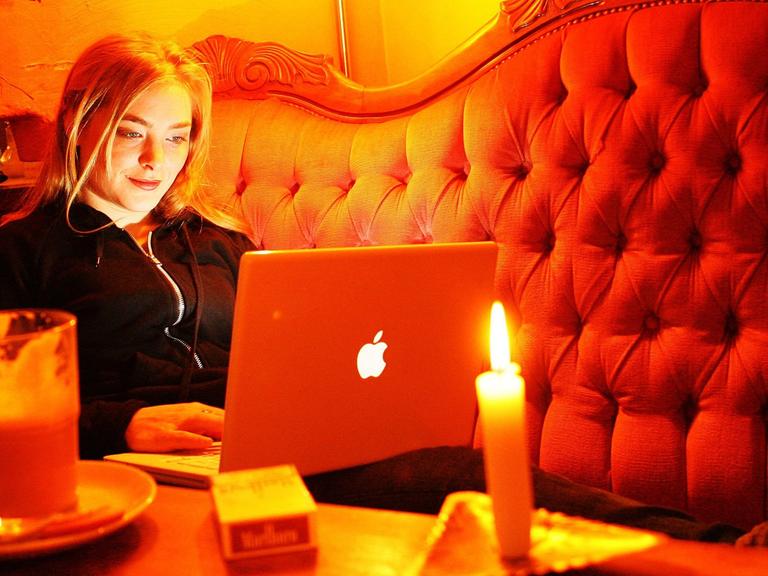 Ein junge Frau sitzt in einem Internetcafe.