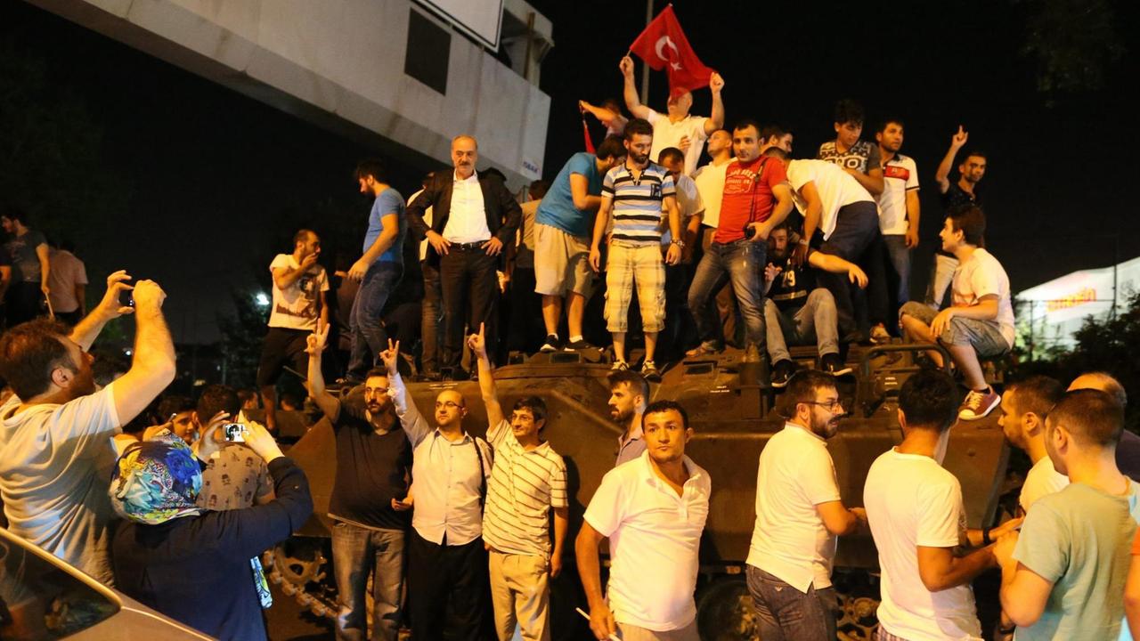 Türken stehen in Istanbul auf einem Panzer.
