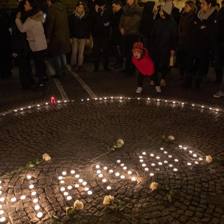 Einen Tag nach der Tat in Hanau: Passanten halten in der Innenstadt mit Kerzen eine Mahnwache für die Opfer ab. 