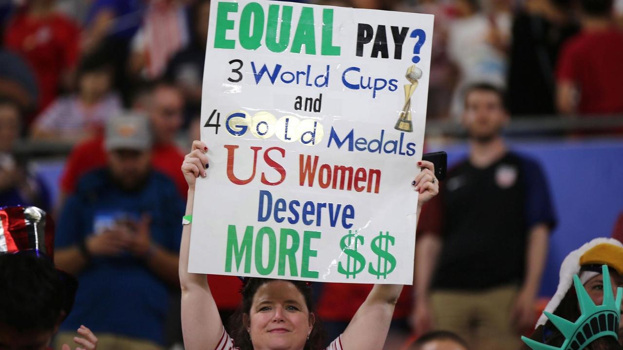 Eine Frau hält am 2. Juli im Stade de Lyon zum WM-Halbfinale ein Plakat hoch mit der Forderung für gleiche Bezahlung im US-amerikanischen Fußball. 
