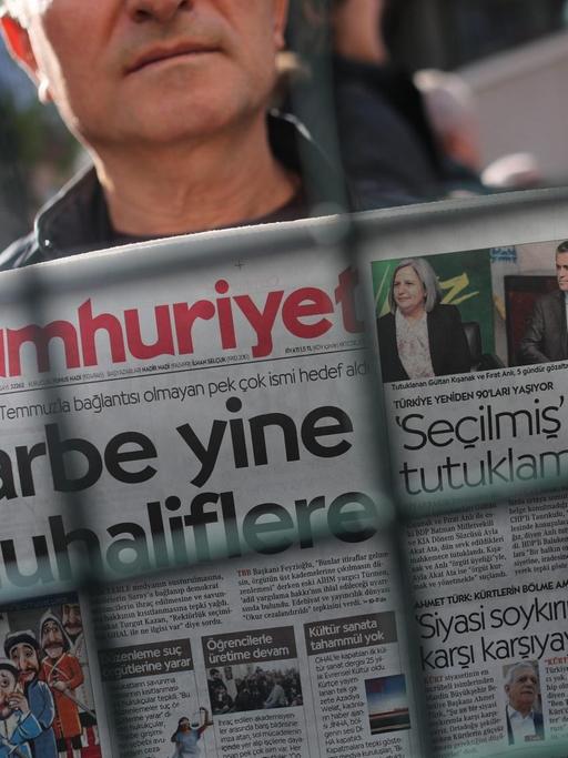 Ein Mann demonstriert mit einer Ausgabe der "Cumhuriyet" gegen die Festnahmen von türkischen Journalisten.