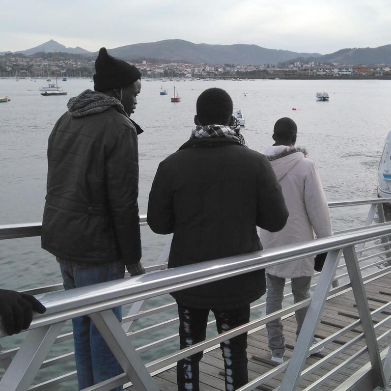 Vier afrikanische Flüchtlinge gehen in der spanischen Stadt Irun über eine Brücke zu einem Fähranleger