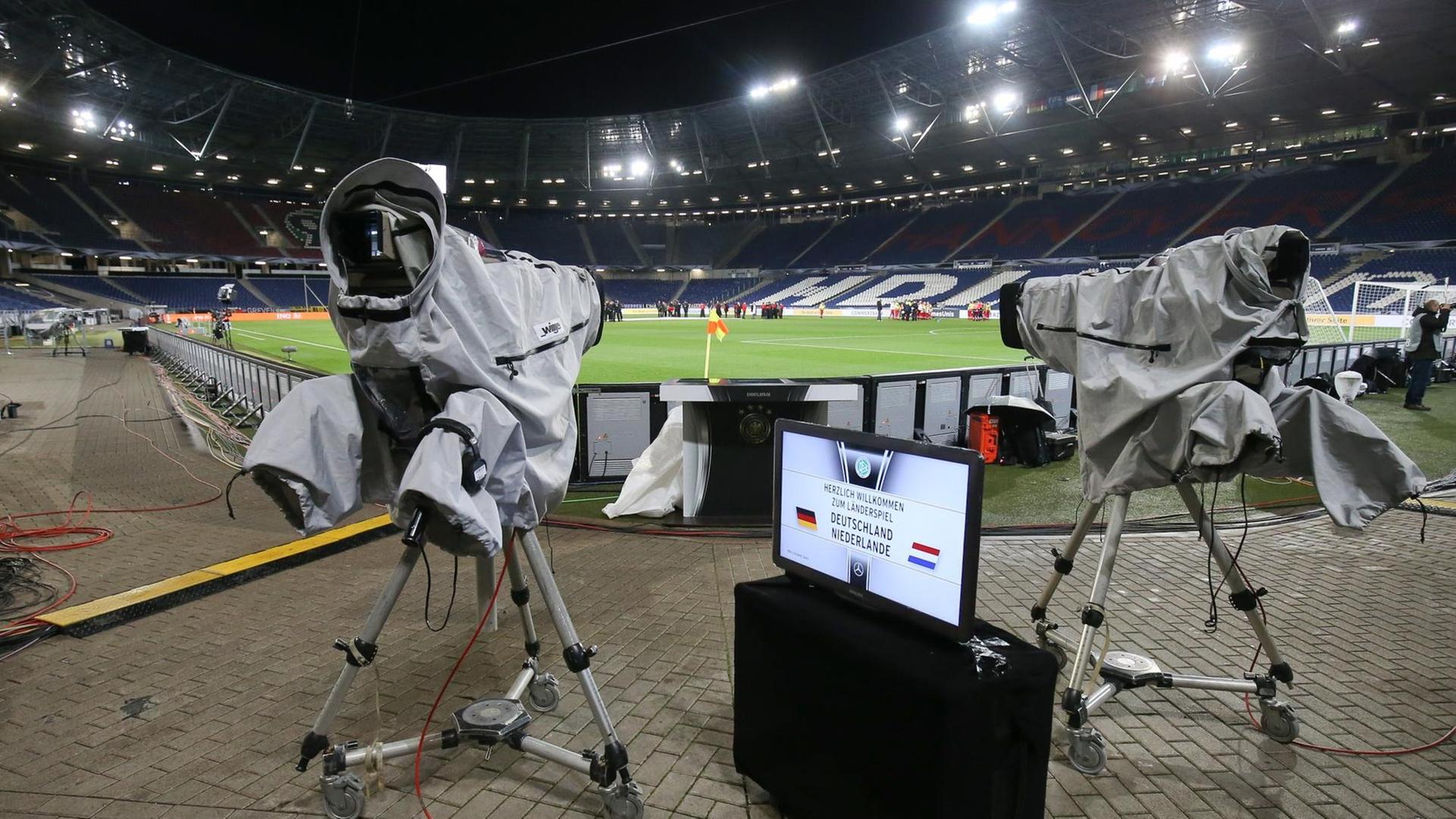 Zu sehen sind Kameras vor einem leeren Fußball-Stadion.