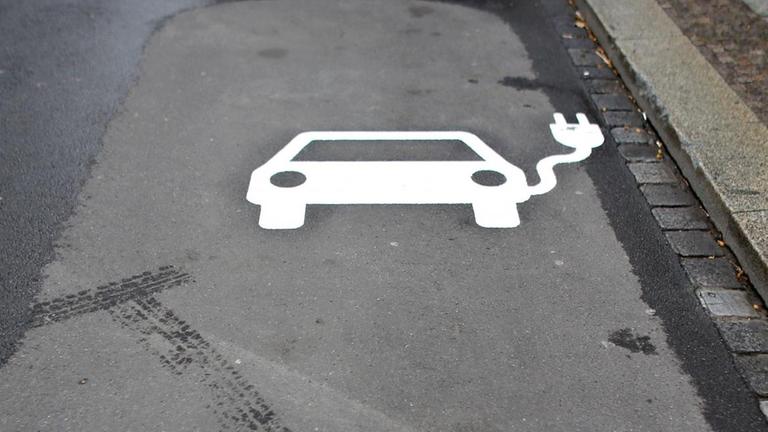Das Symbol eines Autos mit Kabel auf dem Asphalt - ein Parkplatz für Elektroautos.