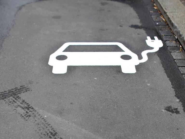 Das Symbol eines Autos mit Kabel auf dem Asphalt - ein Parkplatz für Elektroautos.