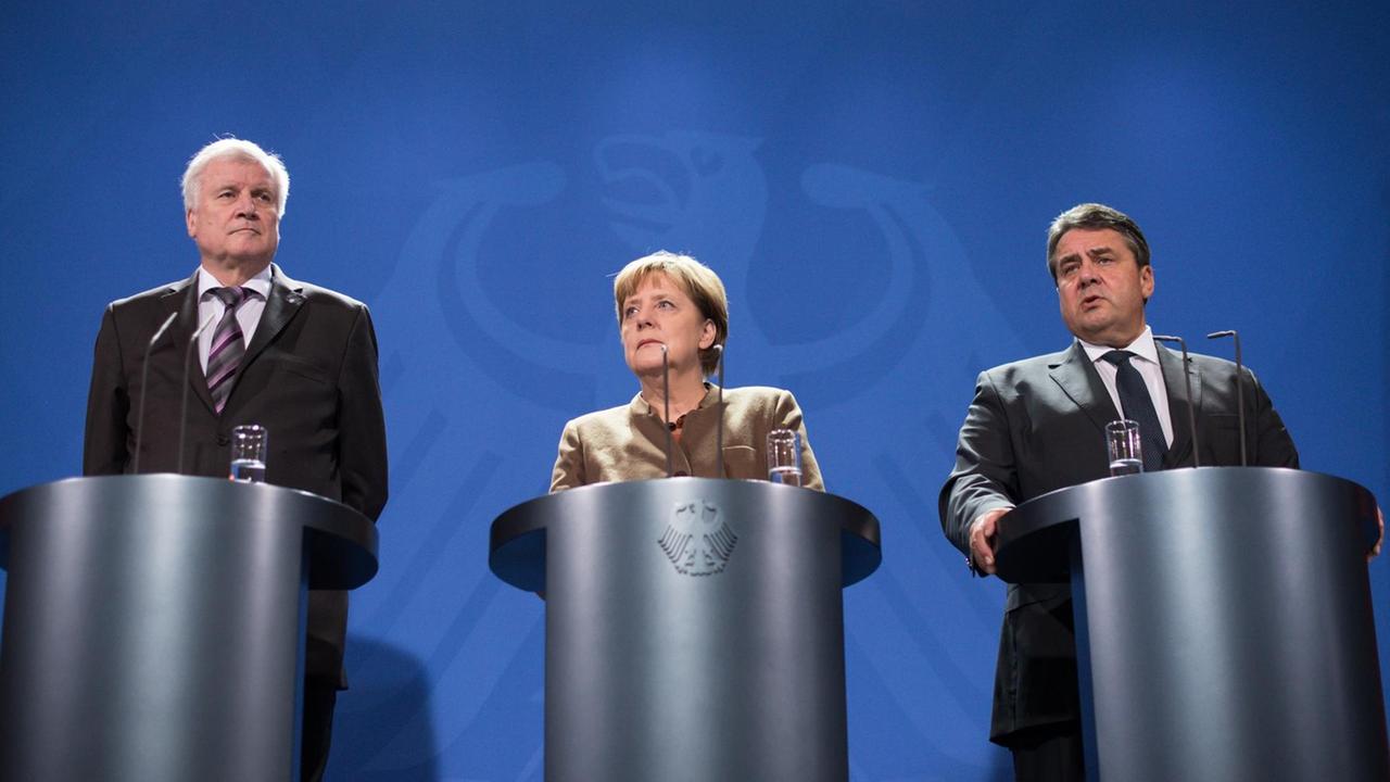 Bundeskanzlerin Angela Merkel, CSU-Chef Horst Seehofer und SPD-Chef Sigmar Gabriel stehen bei einer gemeinsamen Pressekonferenz in Berlin hinter Rednerpulten.
